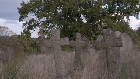 three crucifix cross shaped headstones in overgrown abandoned cemetery