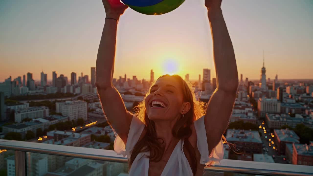 mujer jugando con la pelota de playa en el techo al atardecer sobre la ciudad