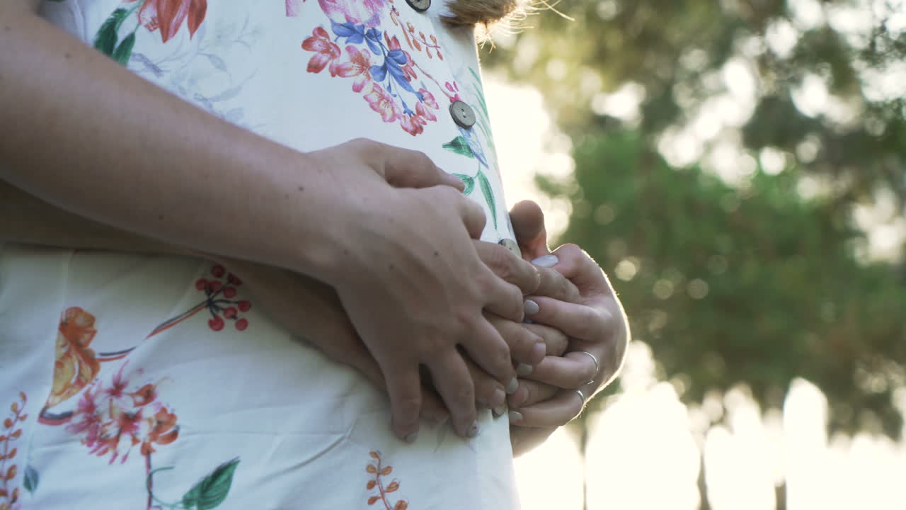 A pregnant couple holding their belly in a floral dress