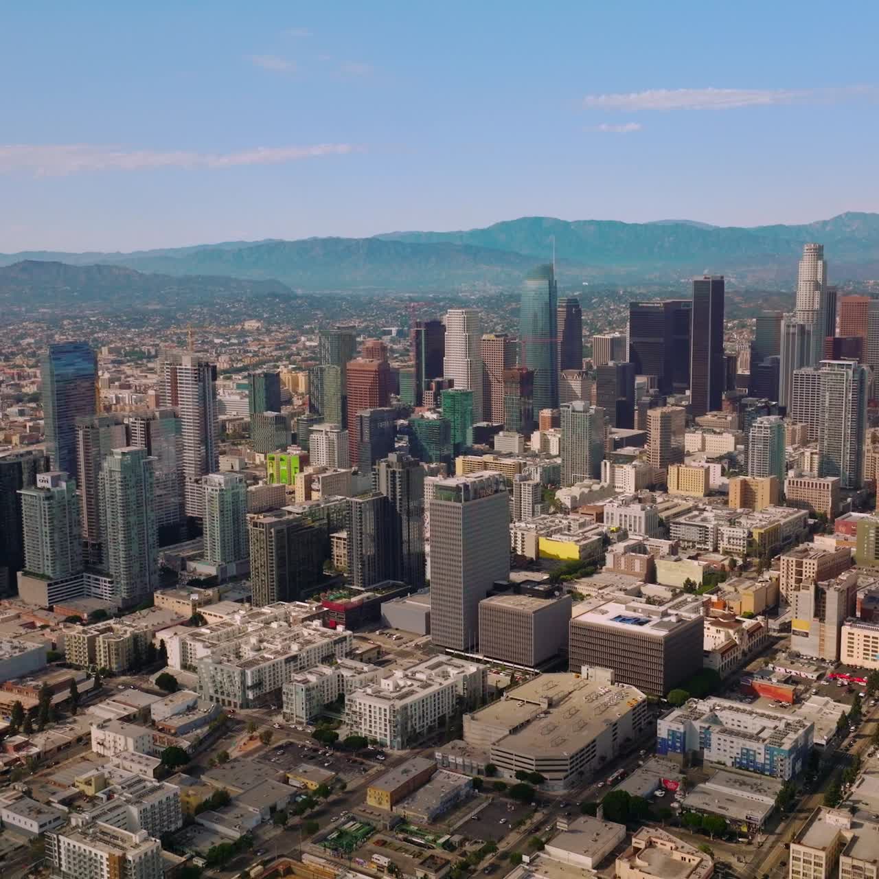 Beautiful skyscrapers of downtown financial centre of Los Angeles, California. Sunny urban scenery stretching up to hazy hills. Blue skies at backdrop