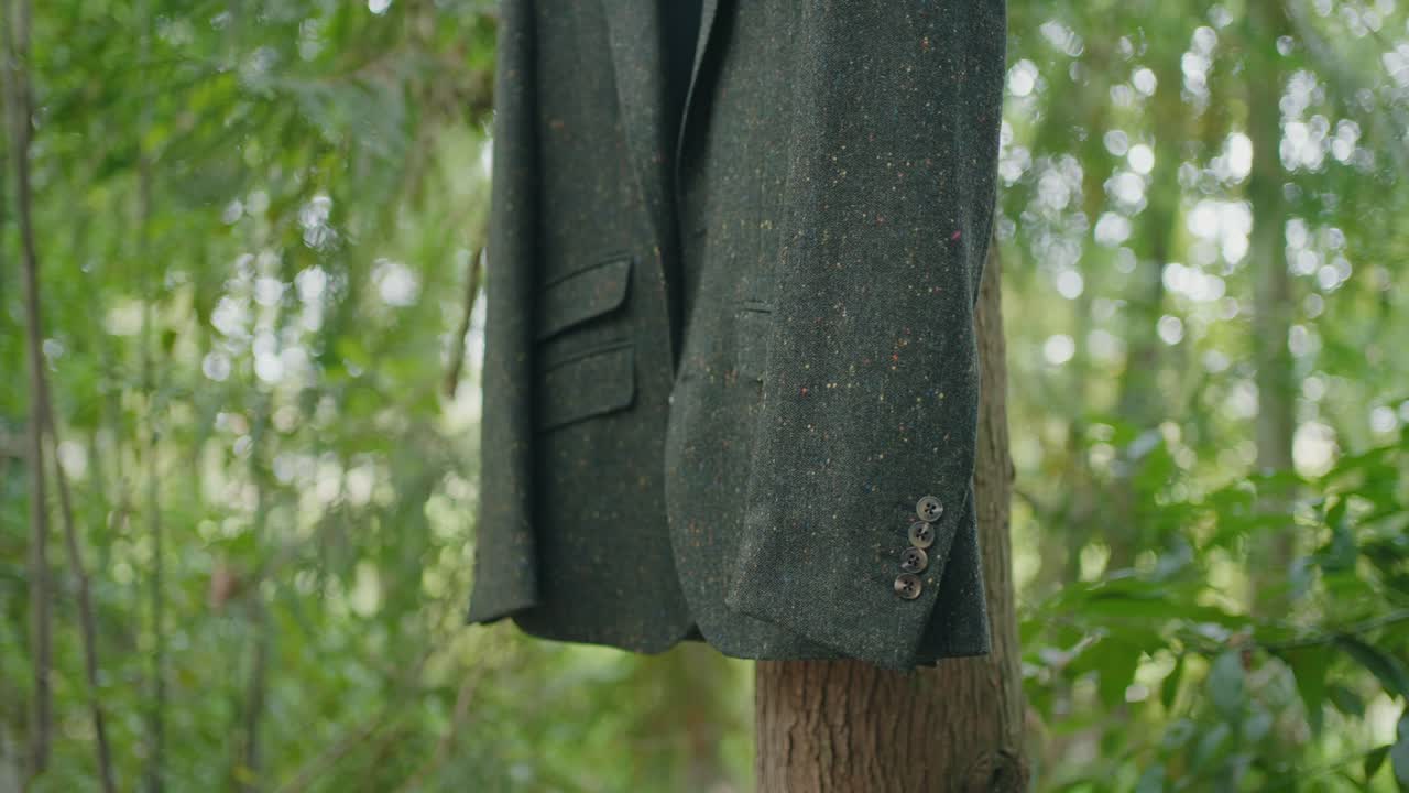 Cappotto scuro appeso a un albero in un ambiente boschivo.
