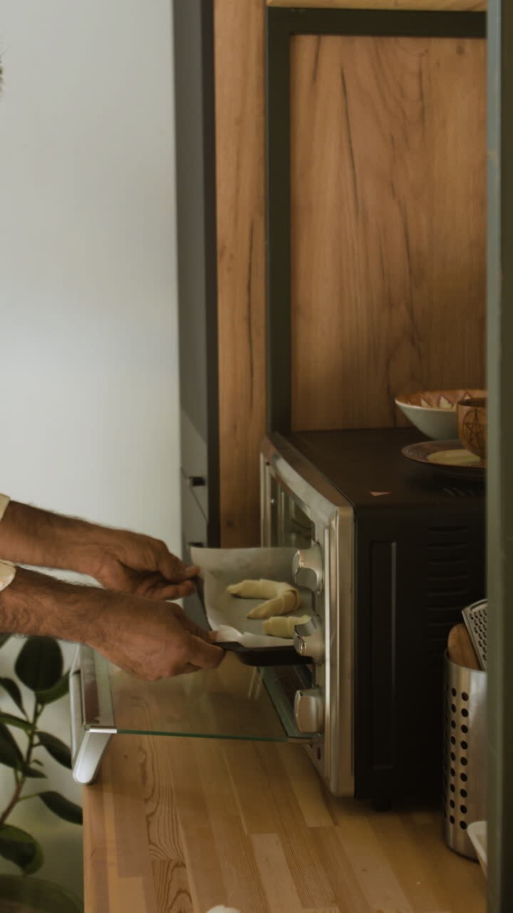 Uomo che inforna croissant in un piccolo forno