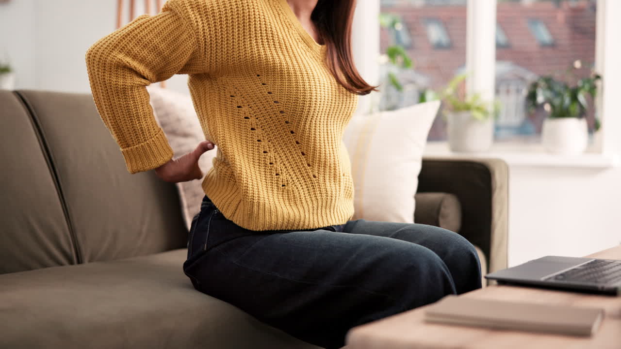 Woman experiencing back pain at home