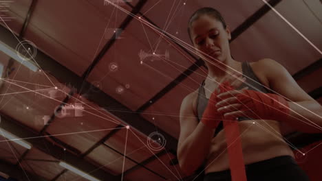 female athlete wrapping red boxing hand wraps in gym displaying fitness data overlay on metal beams
