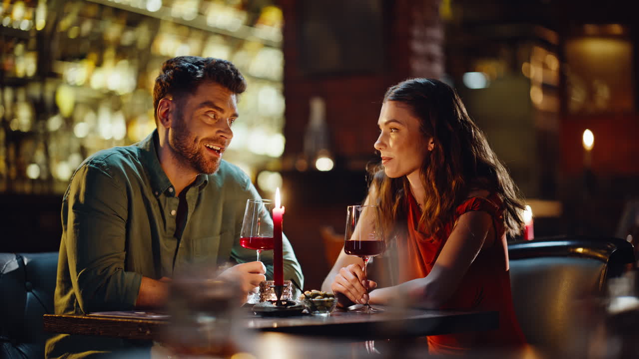 Bellissima coppia che brinda con i calici festeggiando l'anniversario in un ristorante, primo piano