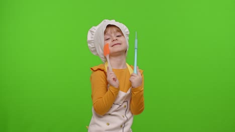 funny child girl kid dressed cook chef baker in apron and hat dancing, fooling around, making faces