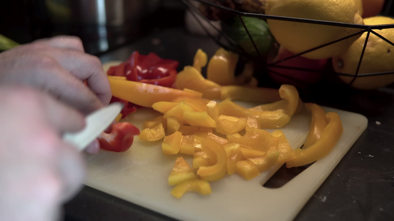 Close up slicing red and yellow peppers, preparing healthy vegetable food