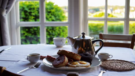 breakfast spread with eggs and pastries on a table by a window