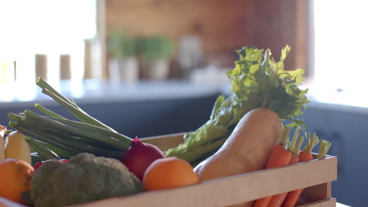 日当たりの良いキッチンカウンターに置かれた有機野菜の木箱のスローモーション映像。