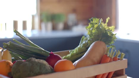 Crate-of-organic-vegetables-on-countertop-in-sunny-kitchen,-slow-motion