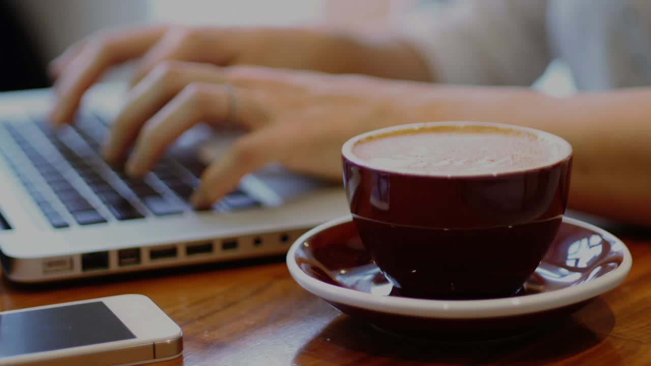 Typing on laptop causing social bubbles growing around phone, coffee cup showing rising engagement