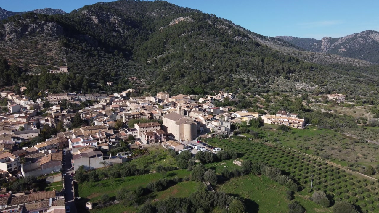 Aerial approach to the village of Caimari, with the Tramuntana mountain range in the background. Mallorca, Spain.