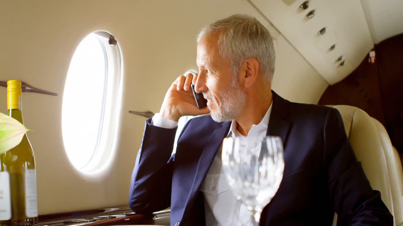 Uomo d'affari che parla al cellulare mentre viaggia su un jet privato 4k