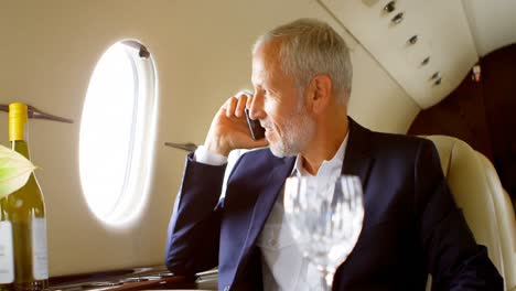 businessman talking on mobile phone while travelling in private jet 4k