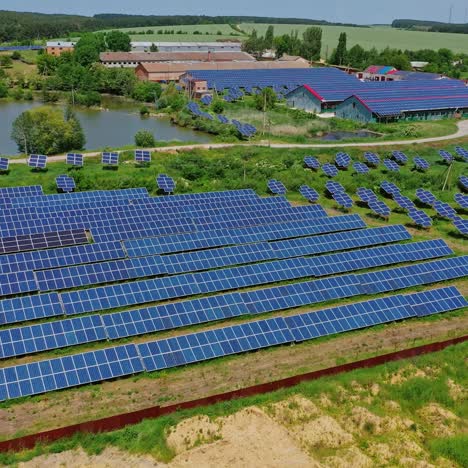 solar power plant among nature. photovoltaic panels in the field and roofs of industrial buildings. renewable clean energy from the sun. aerial view.