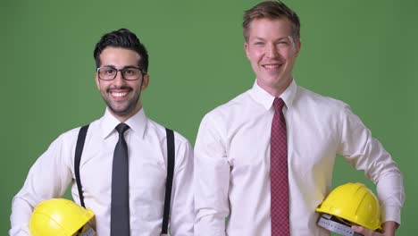 two young multi-ethnic businessmen working together against green background