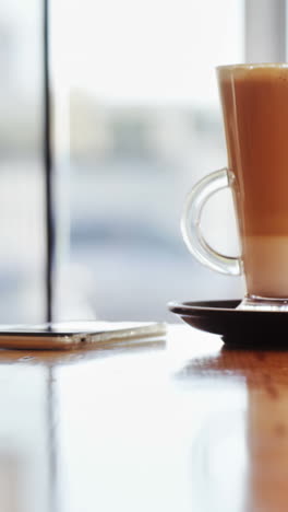 un vaso de café y un teléfono móvil en la mesa