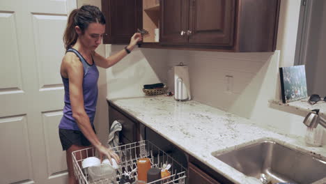 woman unloading clean glassware and dishes from the dishwasher