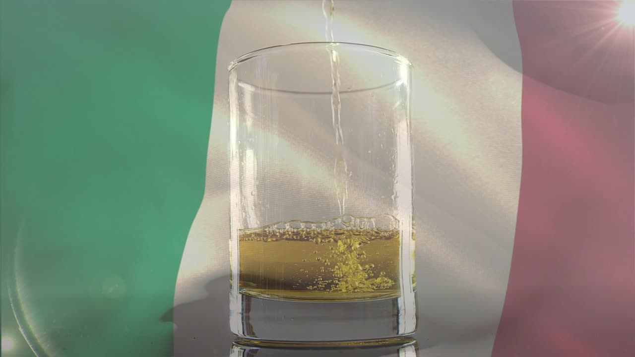 Inizia una mescita fuori dall'inquadratura, un flusso ambrato riempie un bicchiere per mostrare il movimento del liquido su una bandiera tricolore.