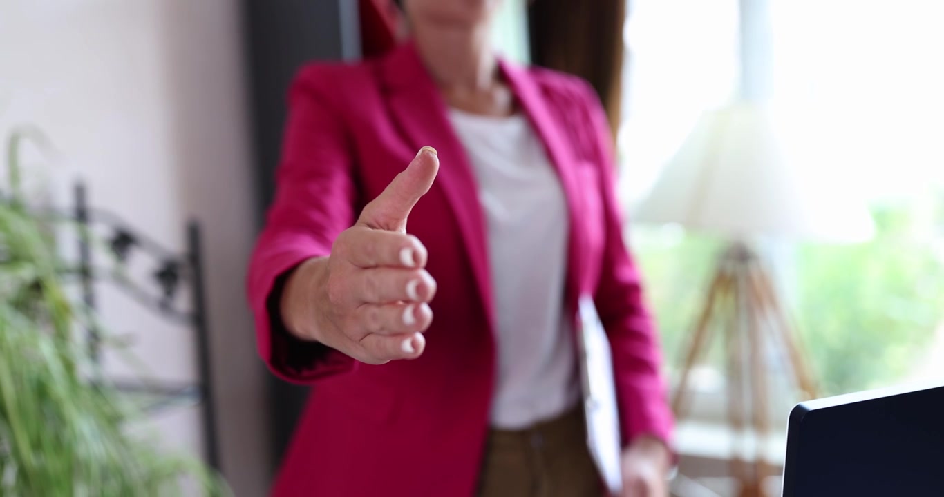 Una donna in ufficio porge una mano per una stretta di mano, primo piano
