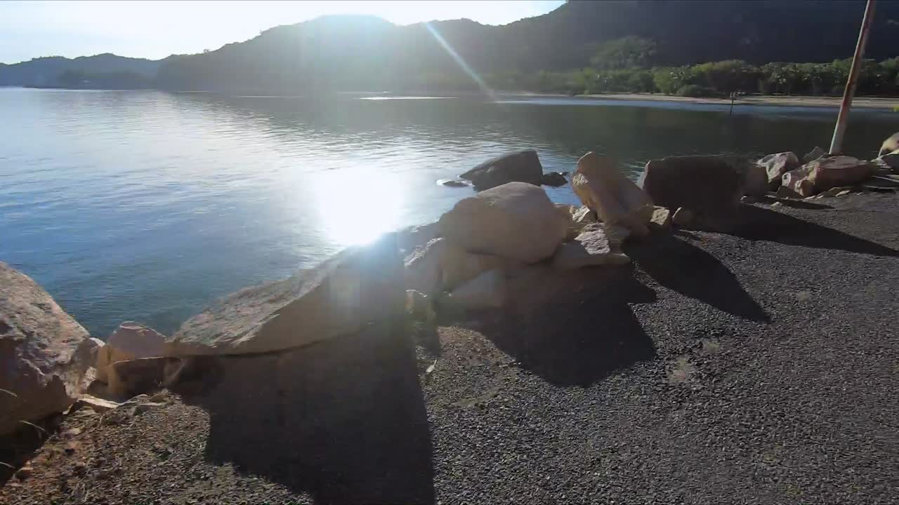 POV(point of view) shot of a man's perspective following a girl biking ahead of him beside the ocean on the tropical island of Magnetic Island in Australia.