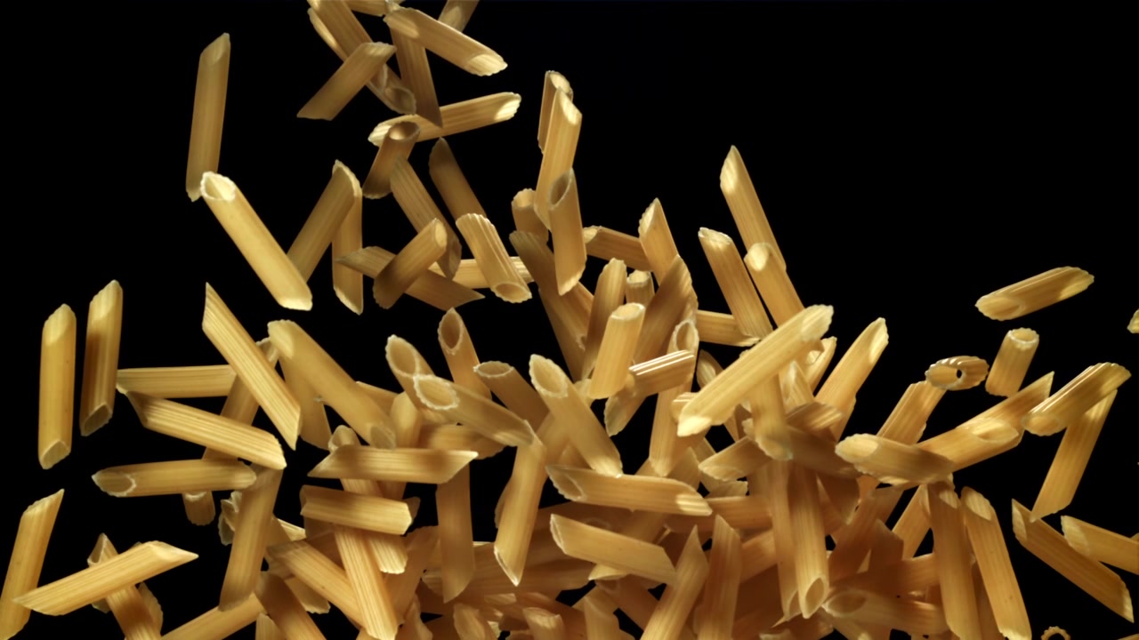 Penne secche che cadono al rallentatore su sfondo nero