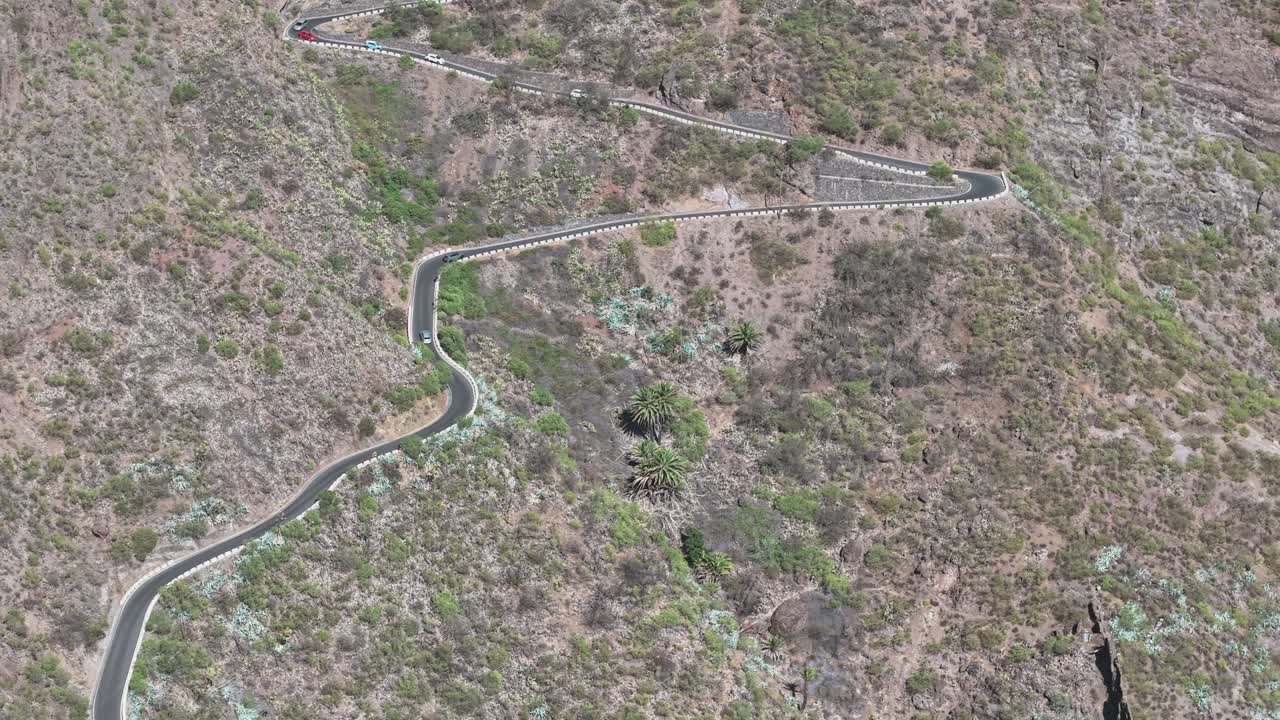 Winding mountain road curves through the arid hills of Tenerife, Canary Islands, Spain, seen from above