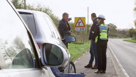 female traffic police officer takes statement from two male drivers at road traffic accident