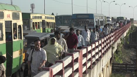 People-walk-down-a-sidewalk-next-to-lanes-of-unmoving-cars-and-buses