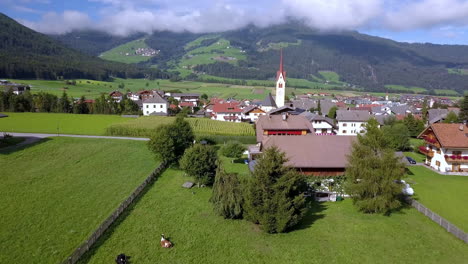 cornfield in valdaora di mezzo near lake braies italy with town panorama, aerial rising reveal shot