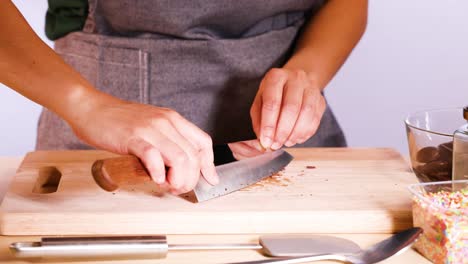 person chopping chocolate discs with a knife