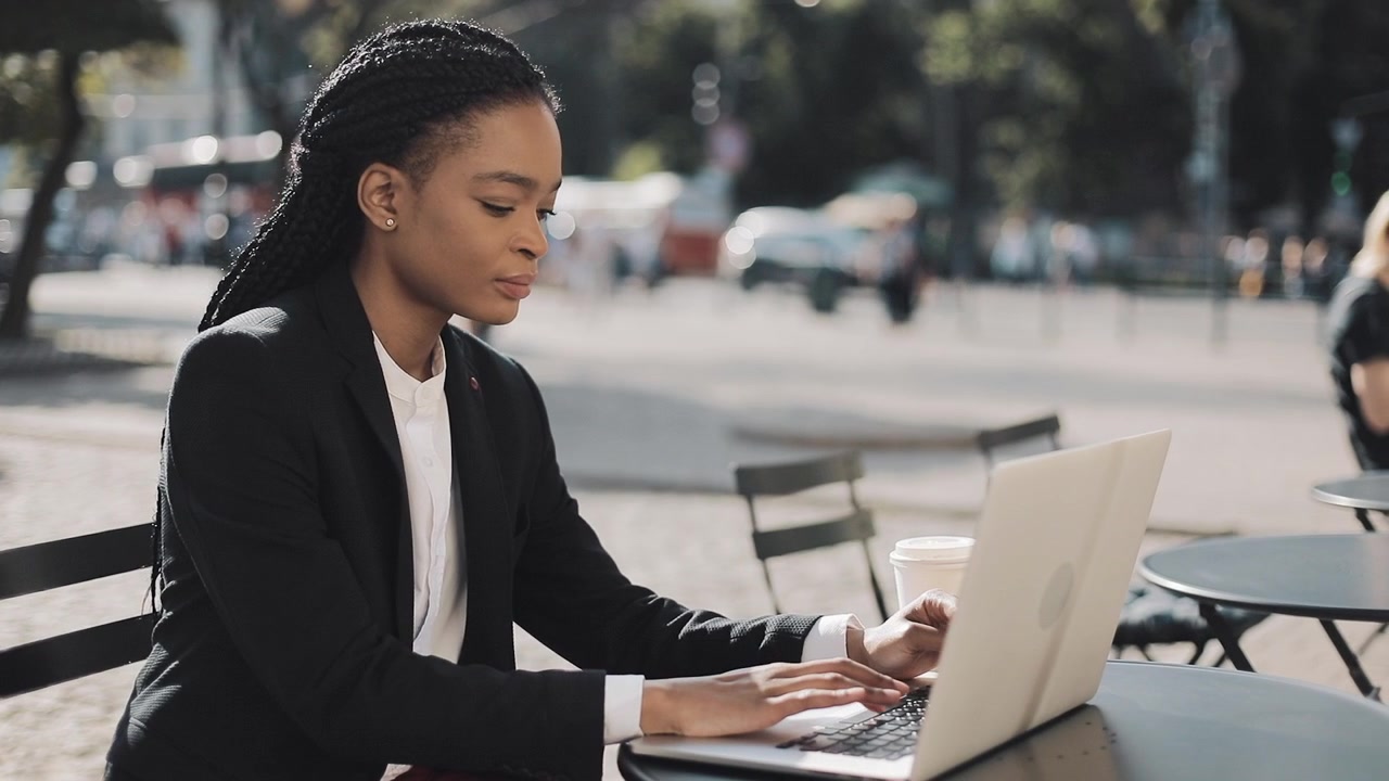 Professional Woman Working on Laptop at Outdoor Cafe