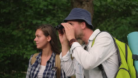 couple hiking in the woods with binoculars