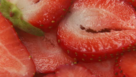 4k súper cerca de fresas en rodajas macro, inclinándose hacia abajo lentamente sobre rodajas de fresa cortadas, fruta saludable