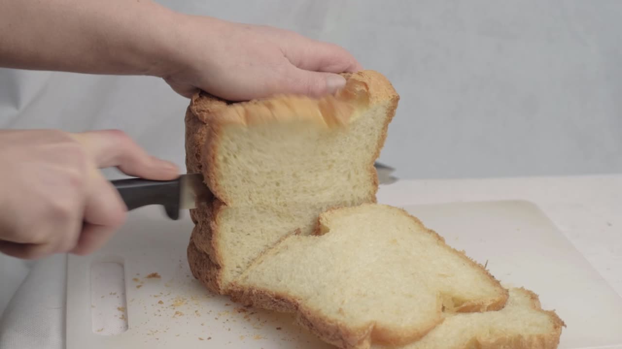 Hand slicing fresh loaf of bread medium shot