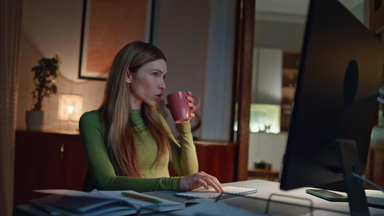 Girl startuper working night looking computer screen drinking coffee close up.