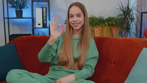 happy cheerful young teen girl looking approvingly at camera showing ok gesture, positive like sign