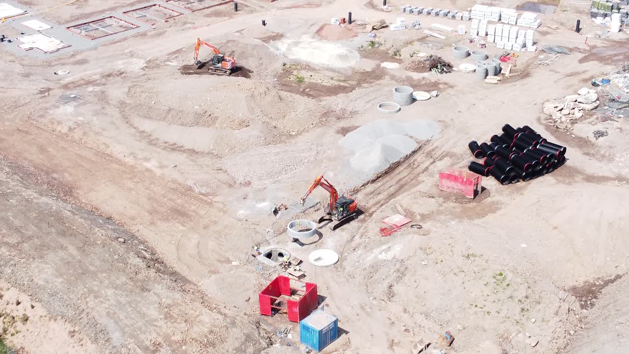 maquinaria de construcción pesada colocando tuberías de residuos de hormigón en el sitio de construcción de bienes raíces vista aérea descendente