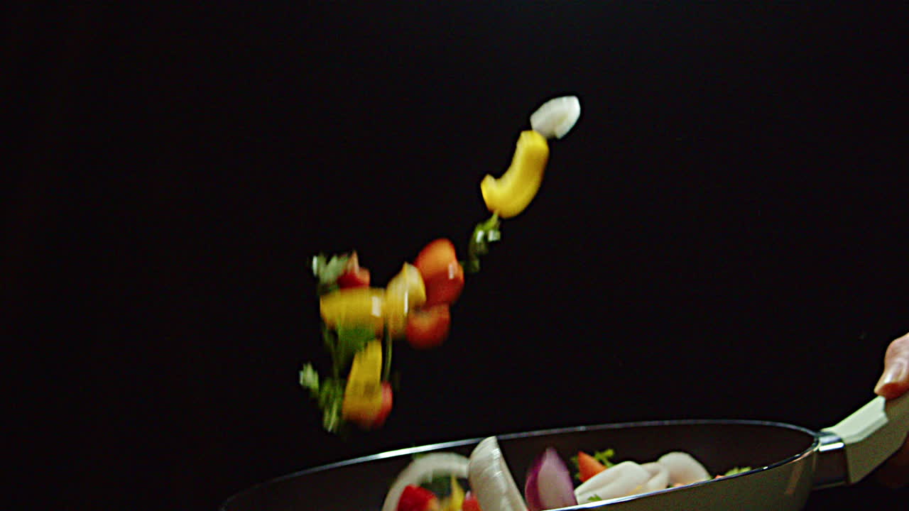 el chef voltea las verduras en la sartén