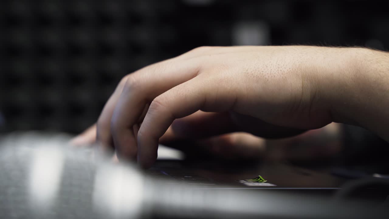 cerrar las manos masculinas escribiendo en el portátil en el estudio de música