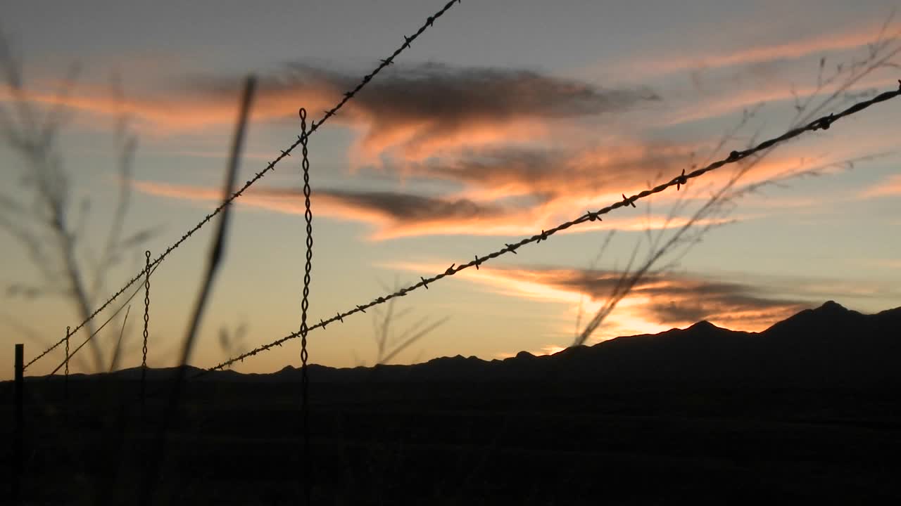 el sol se pone sobre un área protegida por alambre de púas