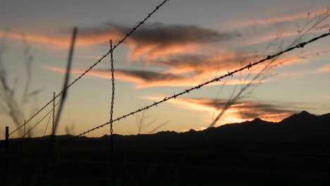 the sun sets over an area protected by barbed wire