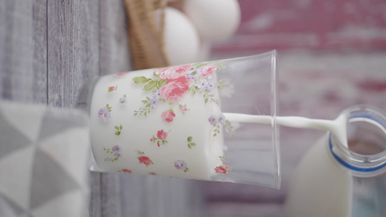 Latte fresco versato in un bicchiere decorativo con motivi floreali
