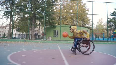 un joven discapacitado juega al baloncesto en la cancha de baloncesto al aire libre.