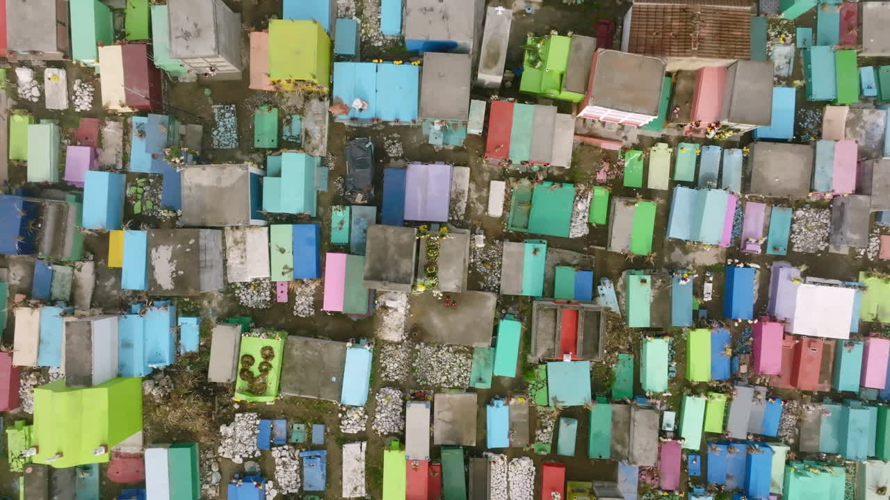 летательный аппарат, движущийся сверху вниз над разноцветными могилами на кладбище