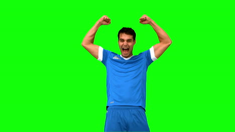 jugador de fútbol feliz levantando los brazos en la pantalla verde