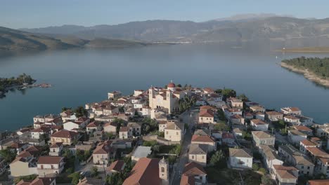 capture an orbiting drone shot of the church of galaxidi, with the gulf appearing in the background