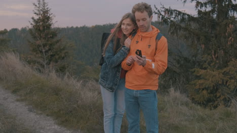 young woman and man backpackers looking at a compass