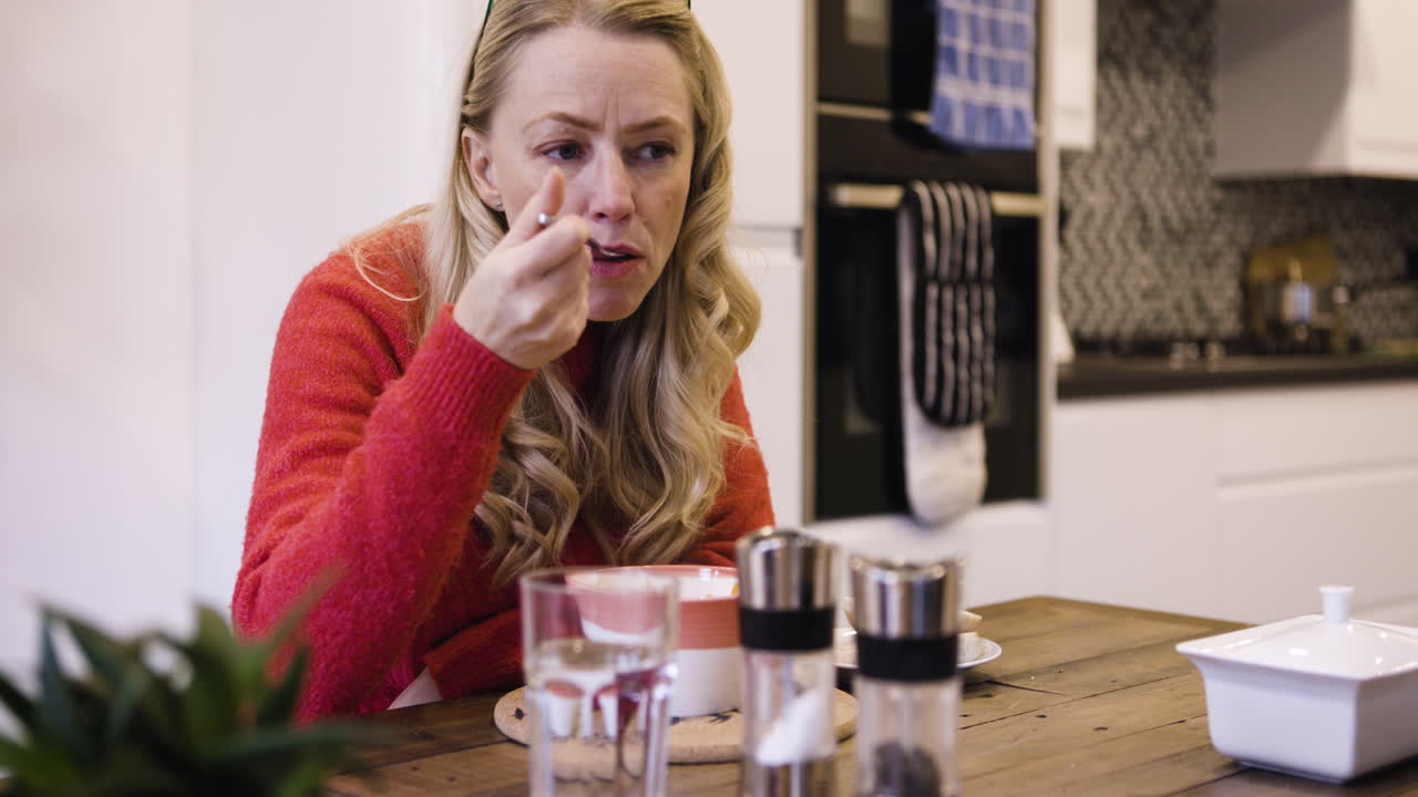 A woman eating soup in the kitchen