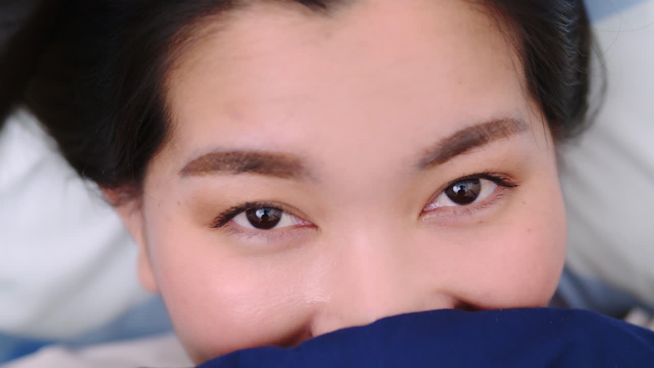 아름 다운 여성 웃 고 카메라와 담요로 덮여 침대에 사랑 스러운 거짓말을 보고